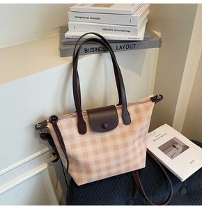 Detail of checkered tote bag showing leather handles and secure snap button closure