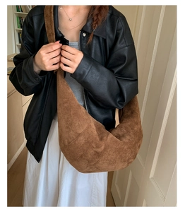 Detail of a large brown vintage croissant bag with textured seams and wide strap