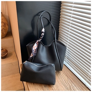 Dettaglio della borsa tote nera a grana di litchi con foulard in seta e pochette