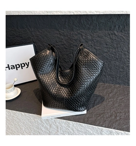 Macro shot of black woven hobo tote bag featuring premium leather texture and logo detail