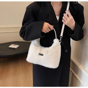 Détail du sac à main en fausse fourrure blanche avec logo argenté et bandoulière