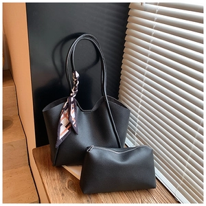Dettaglio borsa tote in pelle nera con pochette piccola e foulard di seta decorativo sulla maniglia