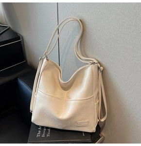 Detail of cream tote bag with adjustable straps and embossed logo on wrinkled faux leather