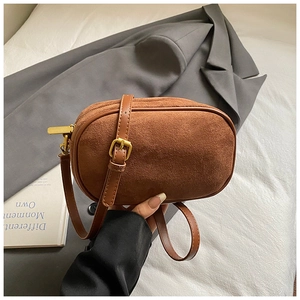 Detailed macro view of a brown suede camera bag with golden hardware and leather trim