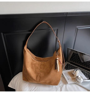 Close-up of brown suede dumpling bag with colorful beaded tassel and wide shoulder strap