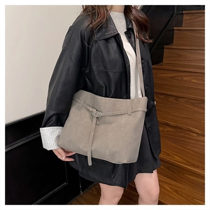 Close-up of a large grey frosted leather tote bag worn as a crossbody on a stylish model