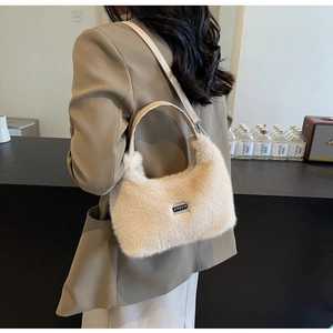 Détail du sac à main en peluche beige avec logo métallique et bandoulière en cuir