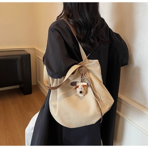 Detail of beige canvas tote with brown leather straps and cute puppy pendant accessory