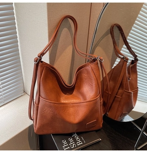Detail of caramel leather vintage tote bag showing texture and brand label in warm light