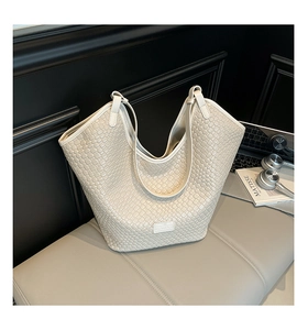Detailed texture of beige woven bucket bag with dual handles and logo patch
