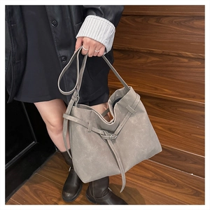 Detail of light grey matte leather tote bag with silver buckle and crossbody strap