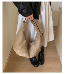 Detail view of large beige croissant crossbody bag with decorative stitching and soft strap