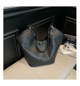 Close-up of black woven leather tote bag showing intricate checkered texture and handle