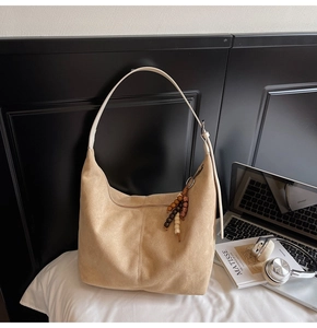 Detail of suede crossbody bag with beaded tassel charm and minimalist design