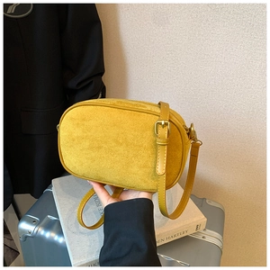 Detail of yellow suede crossbody bag with vintage gold hardware on a retro suitcase