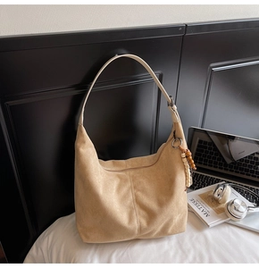 Detail of light camel suede tote bag with colorful wooden bead tassel and leather strap