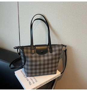 Detail of grey plaid tote bag with black magnetic flap closure and long strap