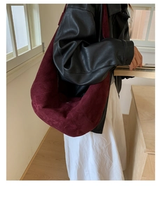 Side view of large burgundy suede dumpling bag showing its spacious capacity and shape