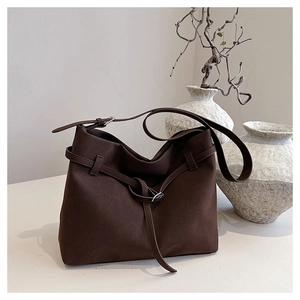Detail of dark brown matte suede tote bag with decorative metal buckle and belt accents