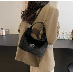 Détail de la texture en fausse fourrure noire et logo en métal sur le sac à main