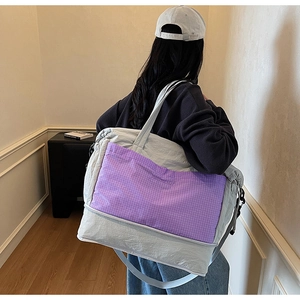 Detail of grey travel tote bag featuring a distinctive purple plaid front pocket design