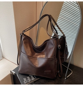 Detail of dark coffee tote bag with dual front pockets and matte leather texture on desk