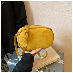 Detail of mustard yellow suede crossbody bag with gold metal hardware and smooth strap