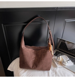 Detailed close-up of dark brown suede shoulder bag with beaded fringe tassel accessory