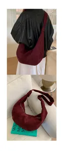Detail of burgundy suede saddle bag with curved stitching and knotted shoulder strap