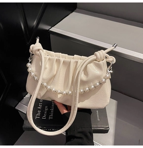 Detailed close-up of cream pleated leather cloud bag with elegant pearl chain and knotted handle