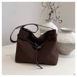 Close-up of a dark brown matte leather tote bag with a decorative silver buckle detail