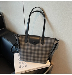 Detail view of plaid tote bag featuring checkered pattern with black leather handles and flap
