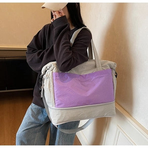 Detail of grey travel tote featuring purple plaid pocket and adjustable shoulder strap