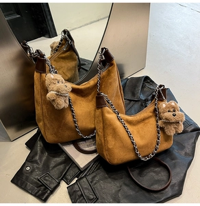 Detail of brown faux suede hobo bag with silver chain strap and plush bear charm