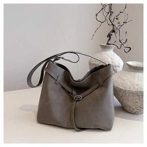 Detail of grey faux suede tote bag with slim decorative strap and silver metal buckle