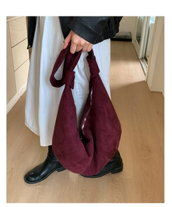 Detail of burgundy oversized suede tote bag featuring a decorative knotted shoulder strap