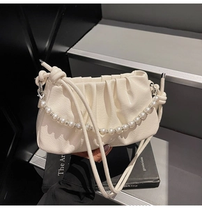 Detail of white pleated cloud bag with pearl chain decoration on artistic books