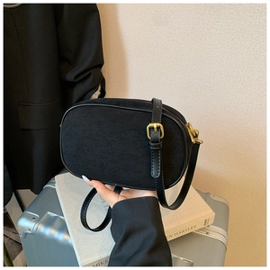 Close-up of matte black vintage crossbody bag featuring gold hardware and suede texture