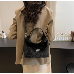 Détail du sac à main en fausse fourrure noire avec logo métallique et bandoulière