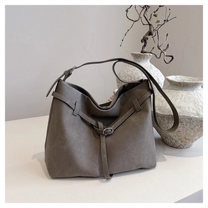 Artistic detail of a taupe suede tote bag with silver buckle and adjustable shoulder strap