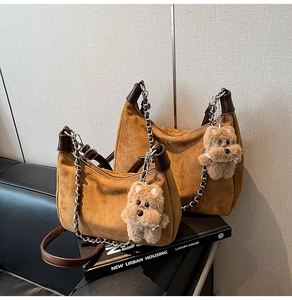Detail of vintage brown suede moon bag with chain strap and cute puppy pendant accessory