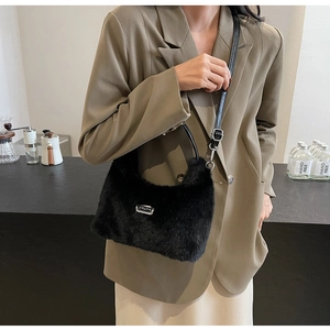 Détail d'un sac bandoulière noir en peluche avec plaque argentée et bandoulière cuir