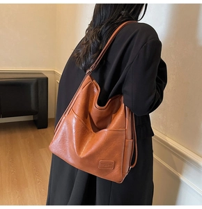 Detailed close-up of brown leather tote bag texture and side pocket on a female model