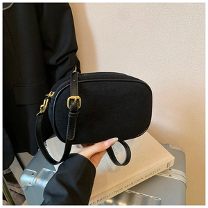 Close-up of black matte suede crossbody bag with gold buckle and adjustable strap