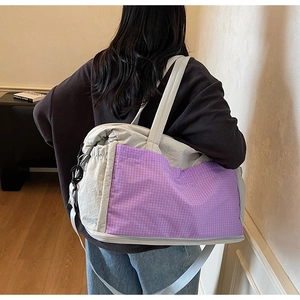Detail of grey nylon travel tote with purple plaid pocket on model in lifestyle setting