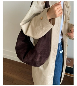 Detail of a large dark brown suede hobo bag styled with a trench coat for city commute