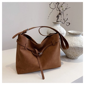 Detail of brown matte suede tote bag featuring a leather strap and metal square buckle