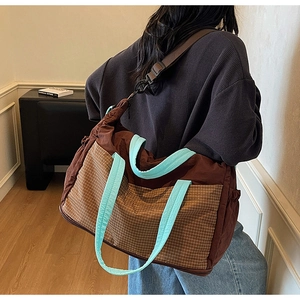 Detail view of the large capacity crossbody bag with brown plaid pocket and blue handles