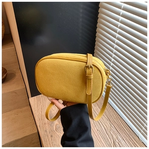 Detail of yellow suede crossbody bag showing matte texture and adjustable leather strap