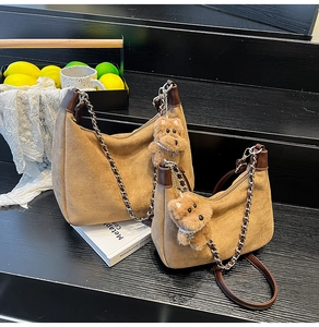 Detailed view of brown suede crossbody bags with silver chains and bear charms